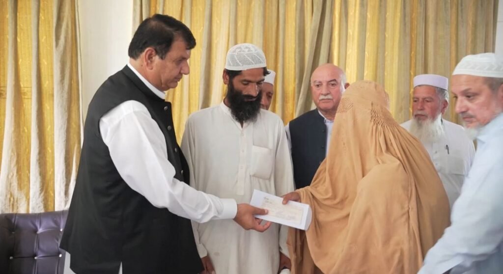 Federal Minister Amir Muqam distributing flood victims compensation cheques in Swat
