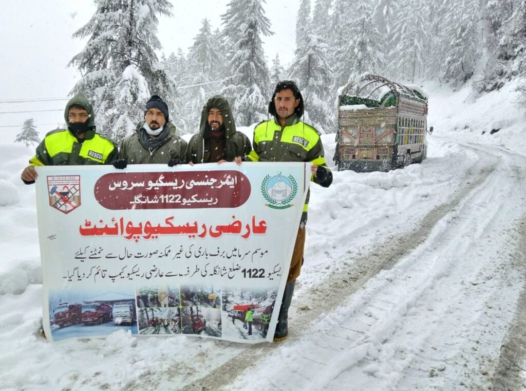 Rescue 1122 personnel conduct relief operations on snow-covered roads in Shangla during heavy snowfall.