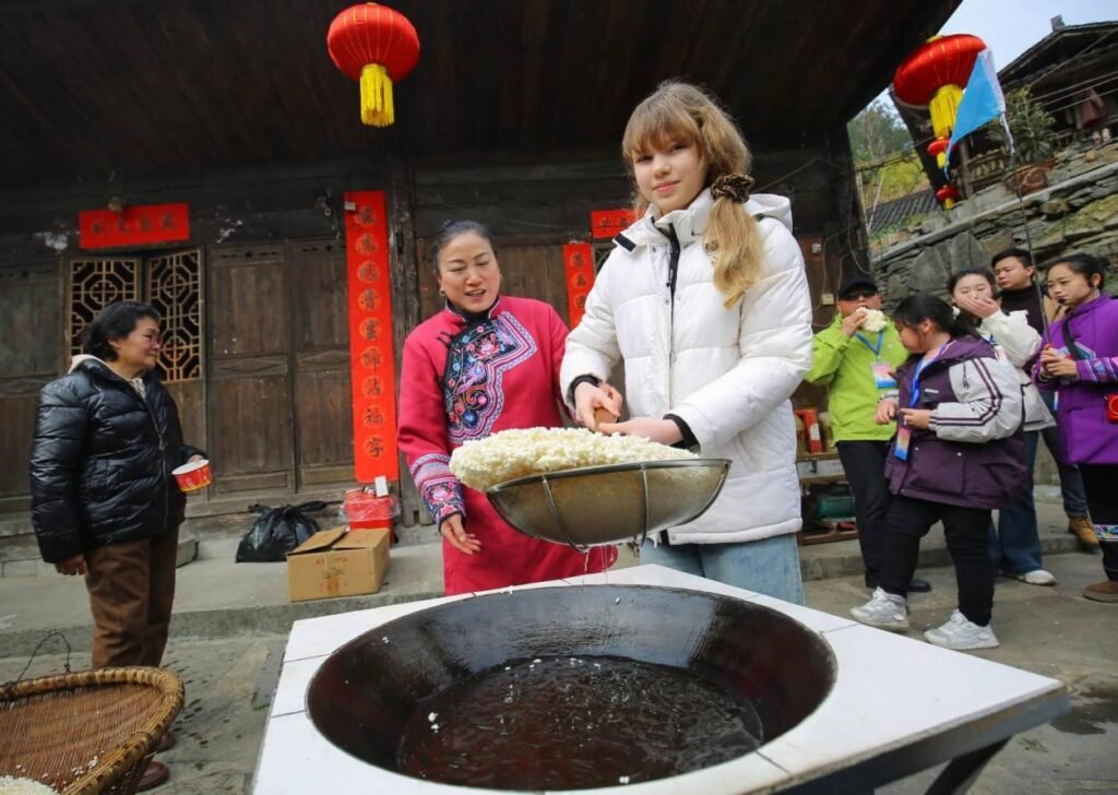 Beyond filtered narratives: China's genuine rural charm wins over global audiences A scenic rural Chinese village with terraced fields and traditional homes attracting international travelers and online audiences.