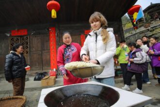 A scenic rural Chinese village with terraced fields and traditional homes attracting international travelers and online audiences.