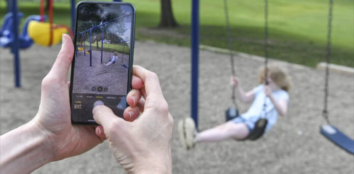 A parent using a smartphone to review privacy settings before sharing a child's photo online.