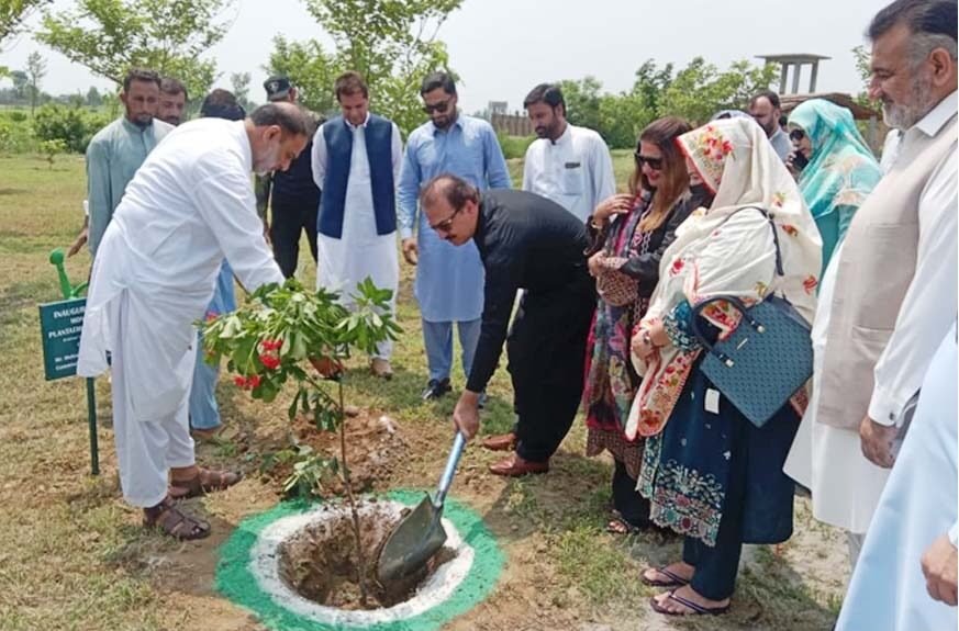 Commissioner Javed Marwat plants a sapling during the tree plantation drive at Women University Mardan.