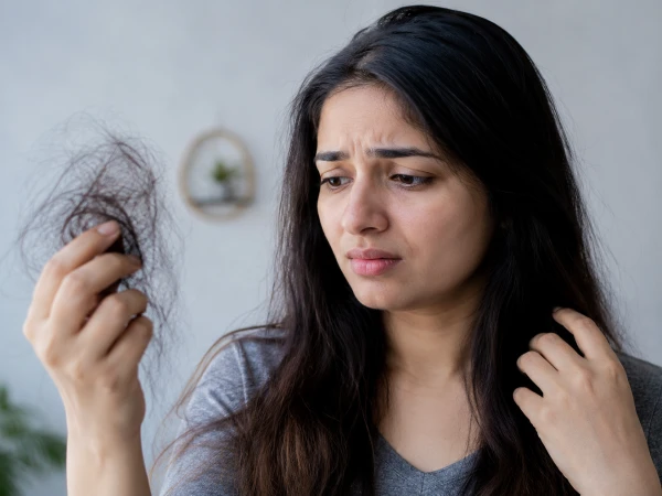 A person experiencing hair loss while checking their scalp, highlighting common causes and hair care tips.