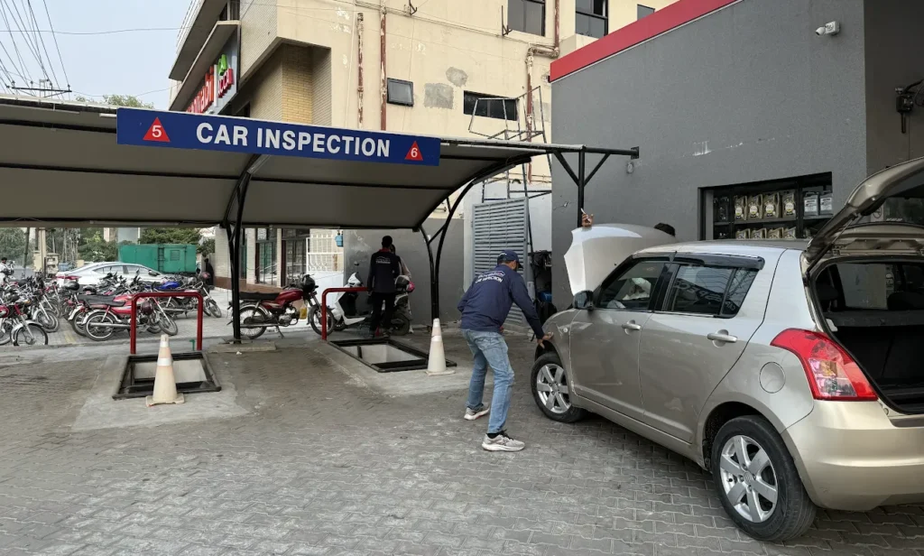 New car undergoing pre-delivery inspection for paint damage, repainted body panels, scratches and accidental repairs at a dealership in Pakistan.
