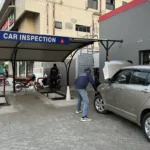 New car undergoing pre-delivery inspection for paint damage, repainted body panels, scratches and accidental repairs at a dealership in Pakistan.